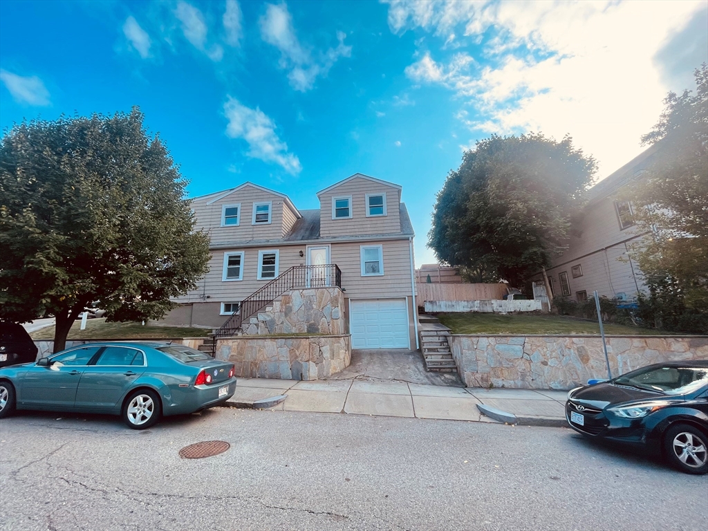 a front view of a house with a garden and parking