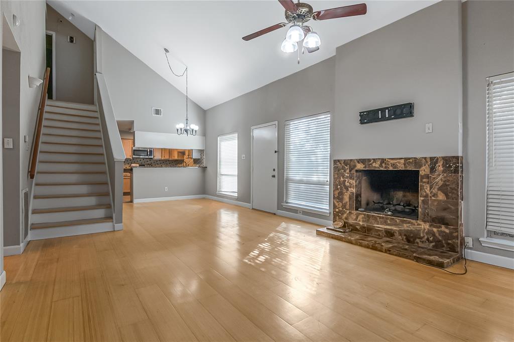 a view of a livingroom with a fireplace a ceiling fan and windows