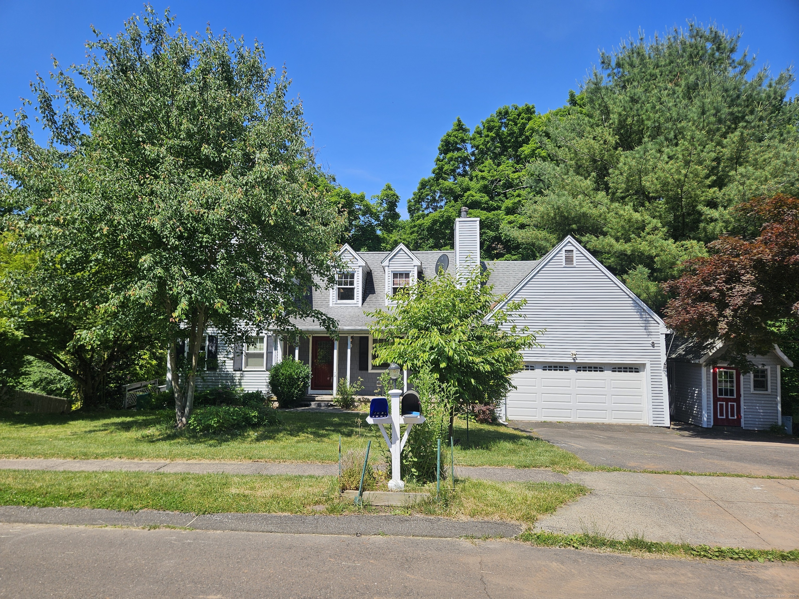 a front view of a house with a garden and trees