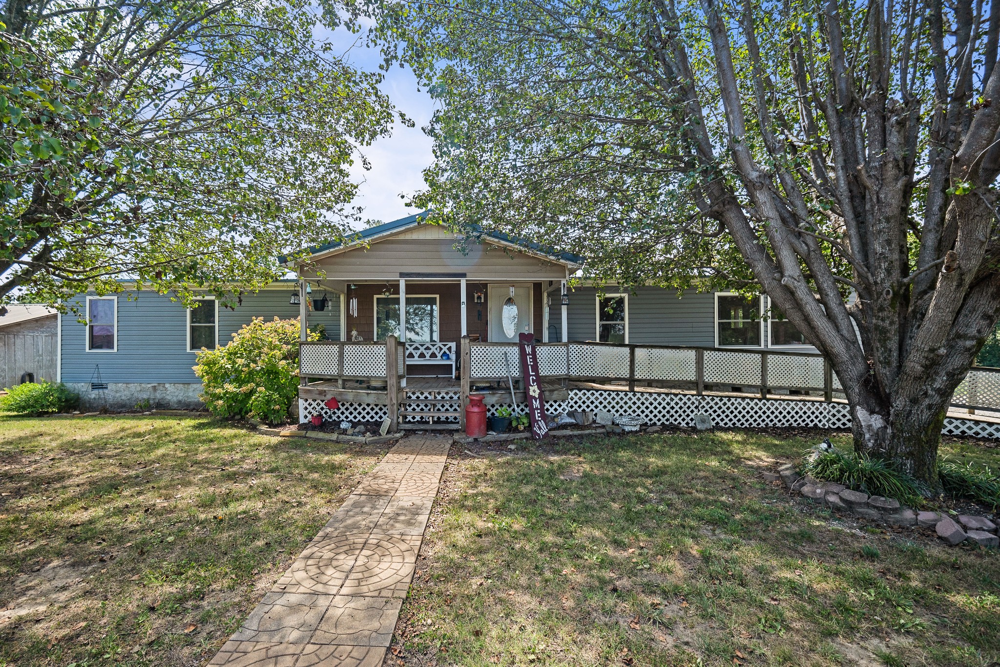 a view of a house with a small yard and a large tree