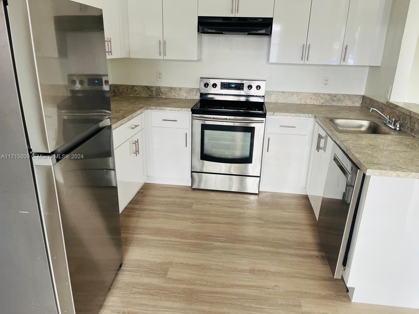 a kitchen with a sink a refrigerator and cabinets