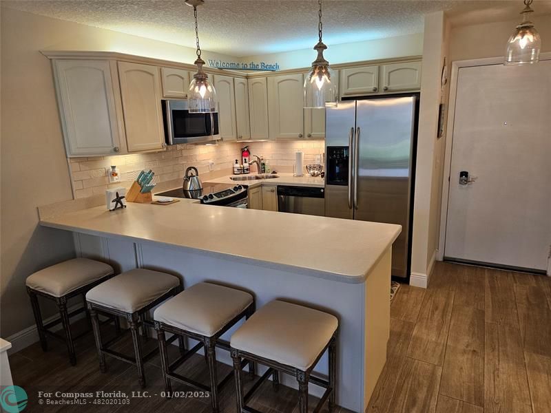 a kitchen with stainless steel appliances a dining table chairs refrigerator and microwave