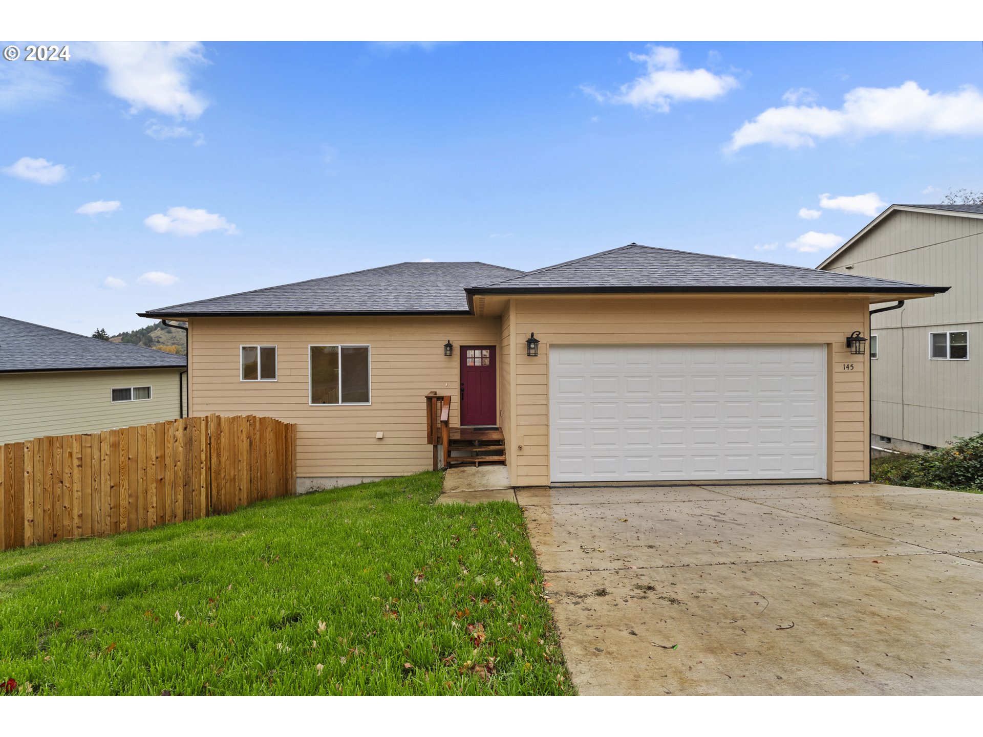 a front view of house with yard and wooden fence