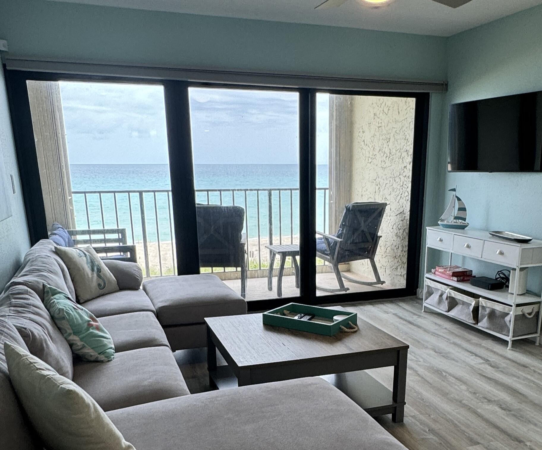 a living room with furniture a flat screen tv and a floor to ceiling window