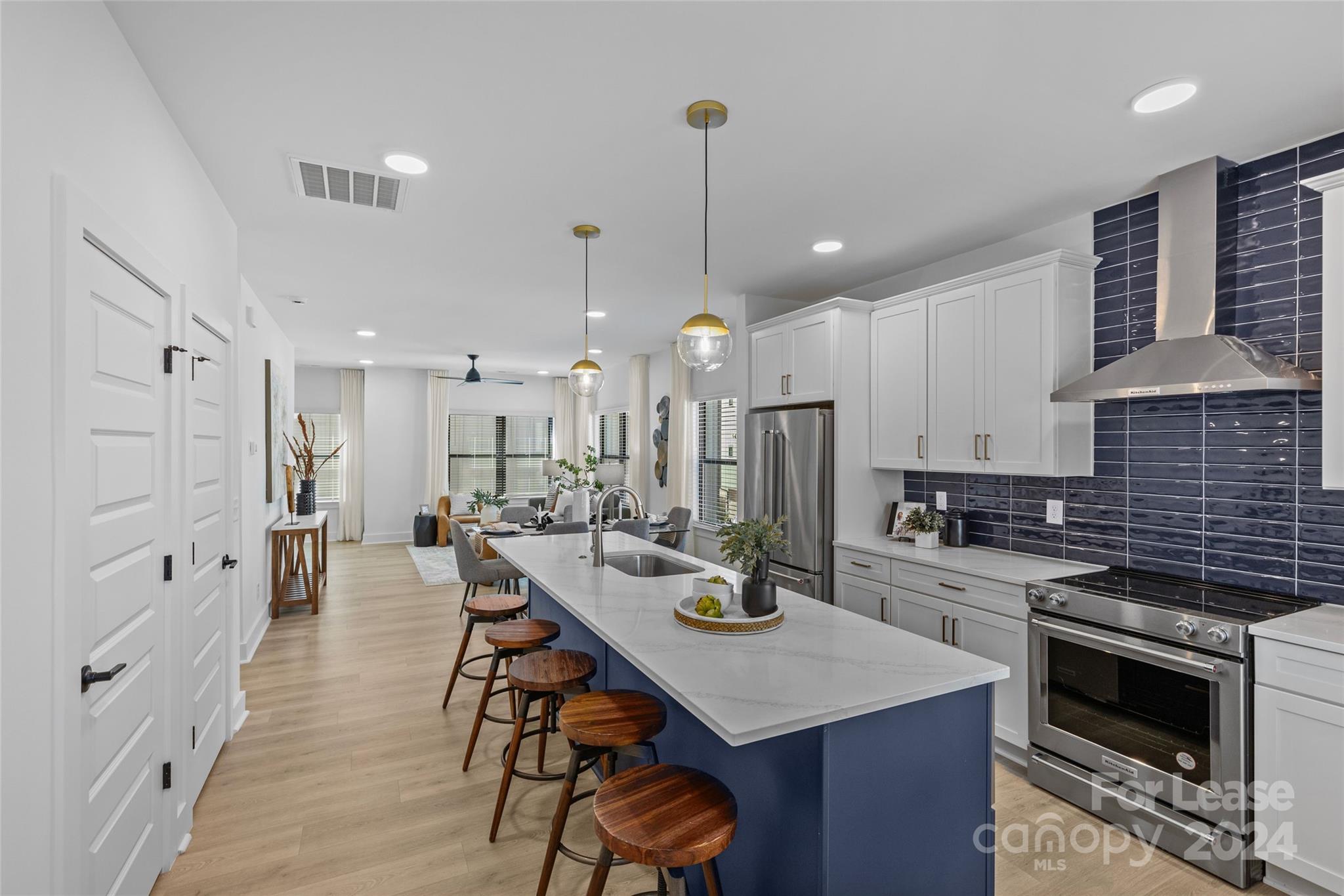 a kitchen with stainless steel appliances kitchen island a table chairs stove and white cabinets