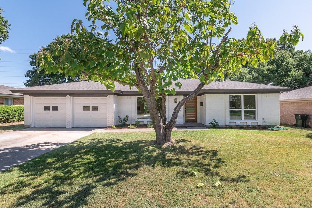 a front view of house with yard and trees in the background