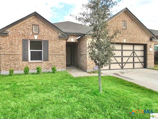 front view of a house with a yard and an trees