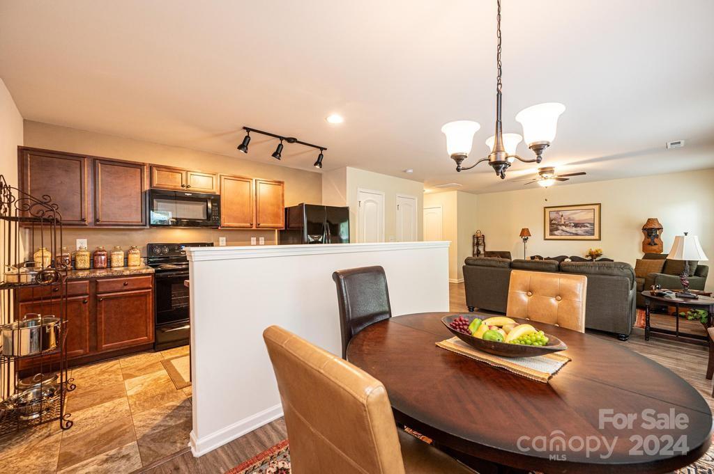 a kitchen with stainless steel appliances kitchen island granite countertop a dining table chairs and a refrigerator