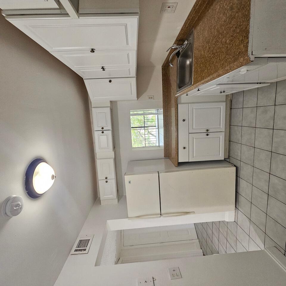 a kitchen with a sink a refrigerator and cabinets