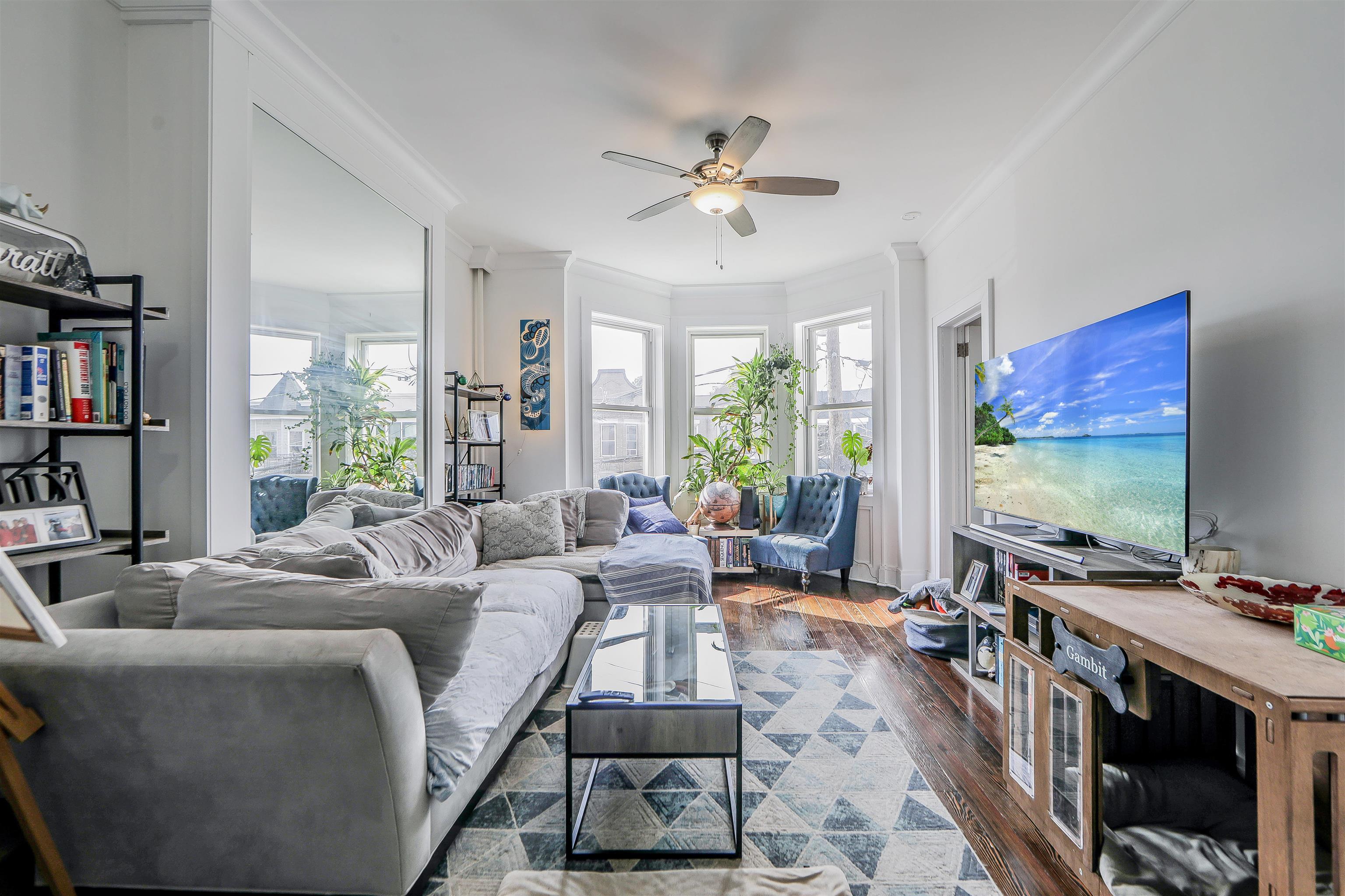 a living room with furniture flat screen tv and a large window