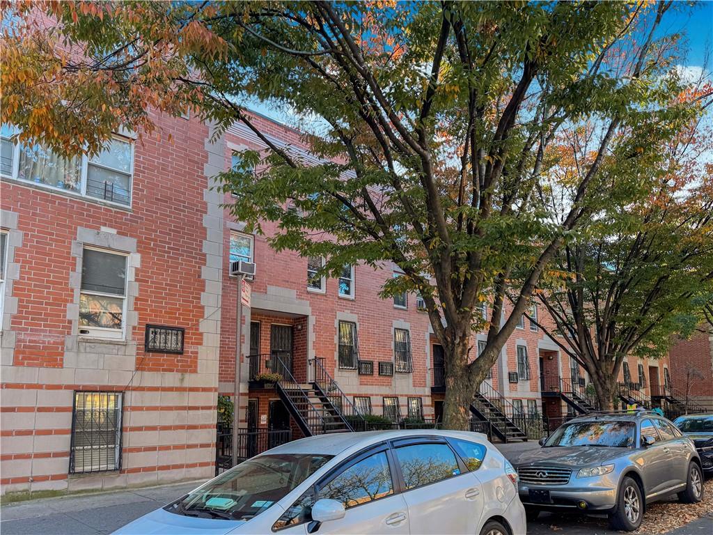 a front view of a building with cars parked