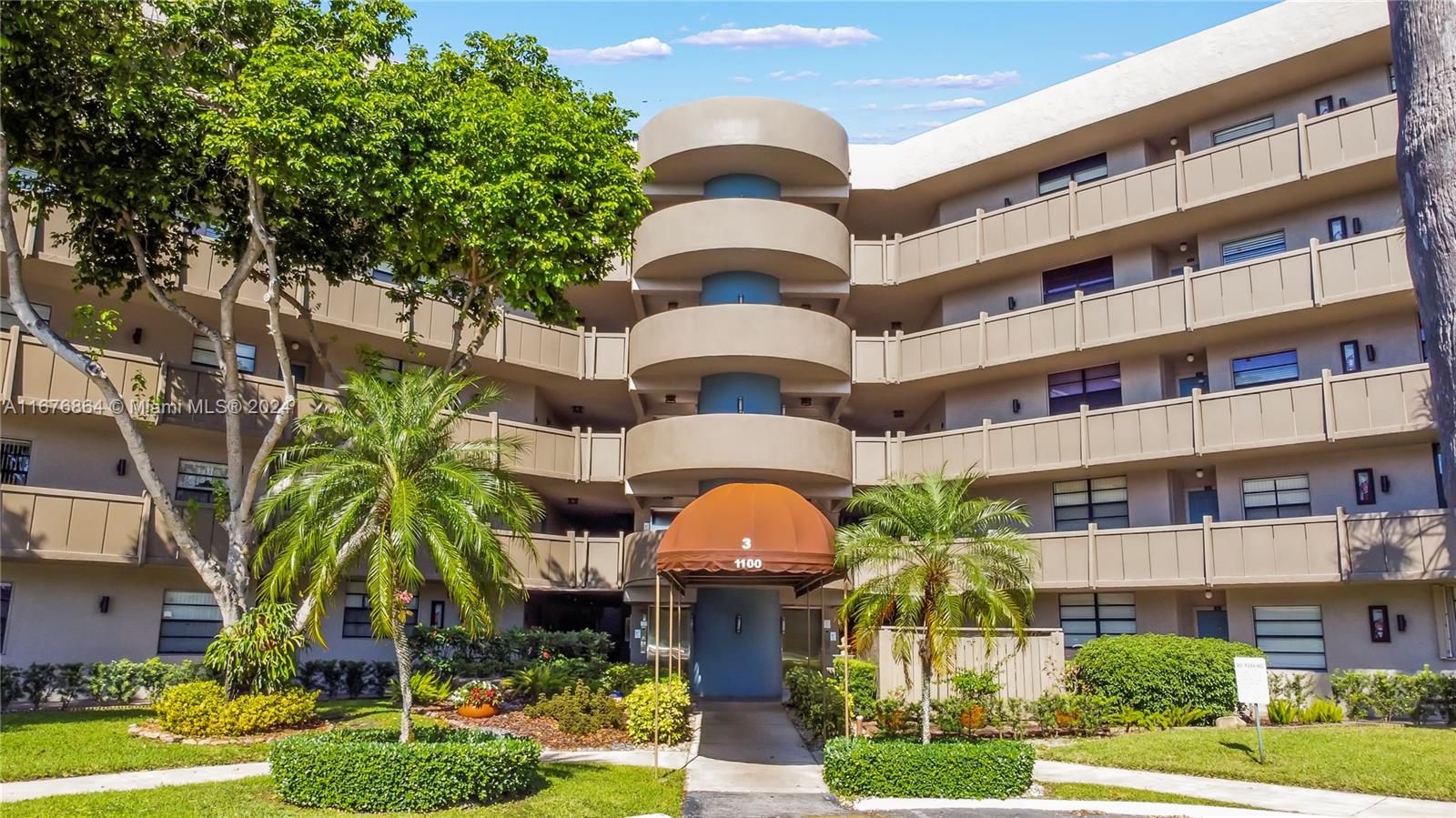 a front view of multi story residential apartment building with yard and parking space