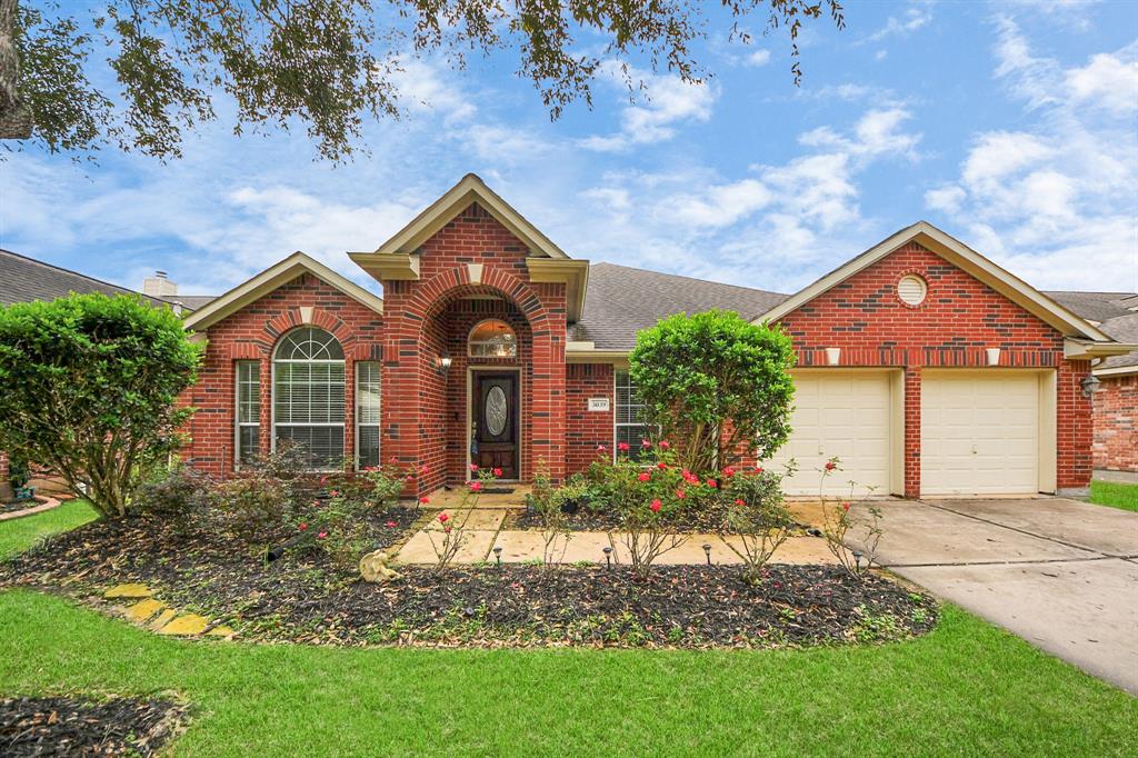 Charming brick home with a welcoming front entrance, well-maintained lawn, and mature trees.