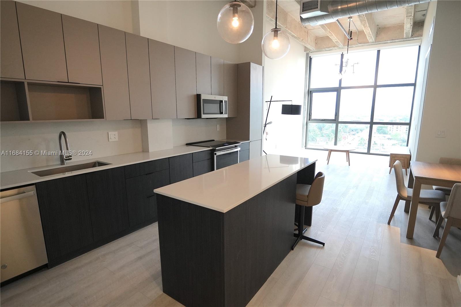 a kitchen with stainless steel appliances kitchen island granite countertop a sink counter space and a large window