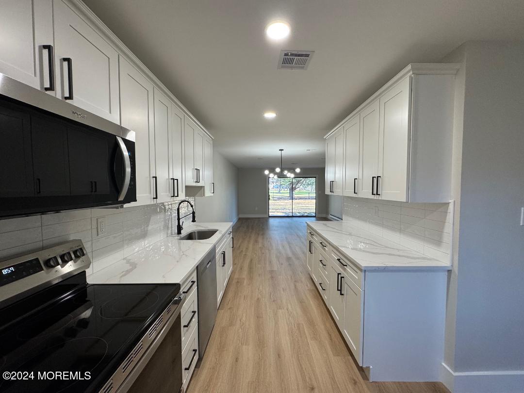 a kitchen with stainless steel appliances granite countertop a stove a sink and a microwave