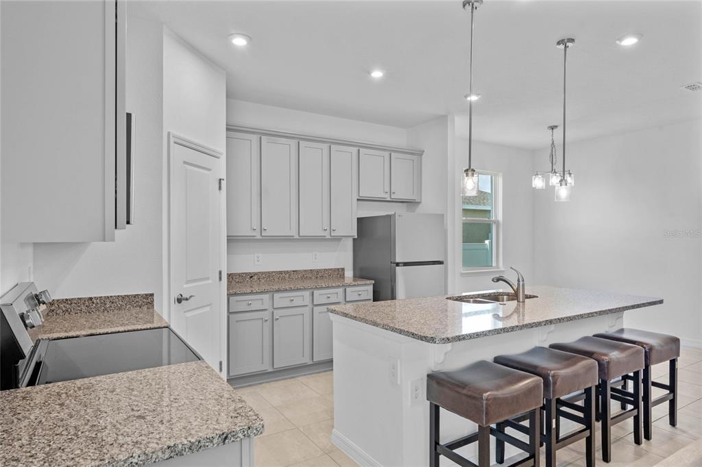 a kitchen with kitchen island a dining table chairs sink and cabinets