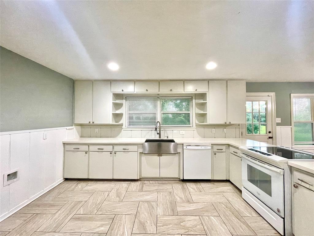 a large white kitchen with stainless steel appliances granite countertop a sink and dishwasher a stove top oven with white cabinets