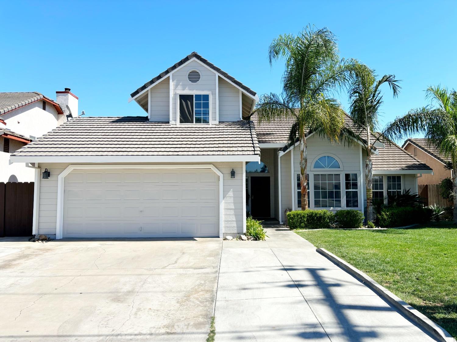 a front view of a house with a yard and potted plants