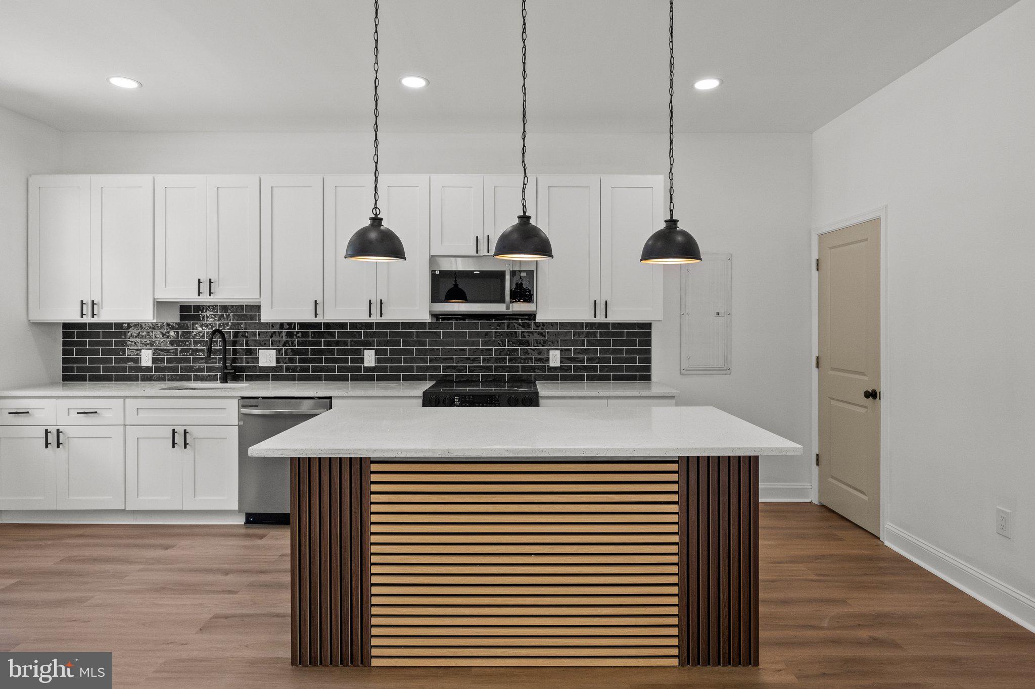 a kitchen with stainless steel appliances kitchen island granite countertop a sink a stove and white cabinets