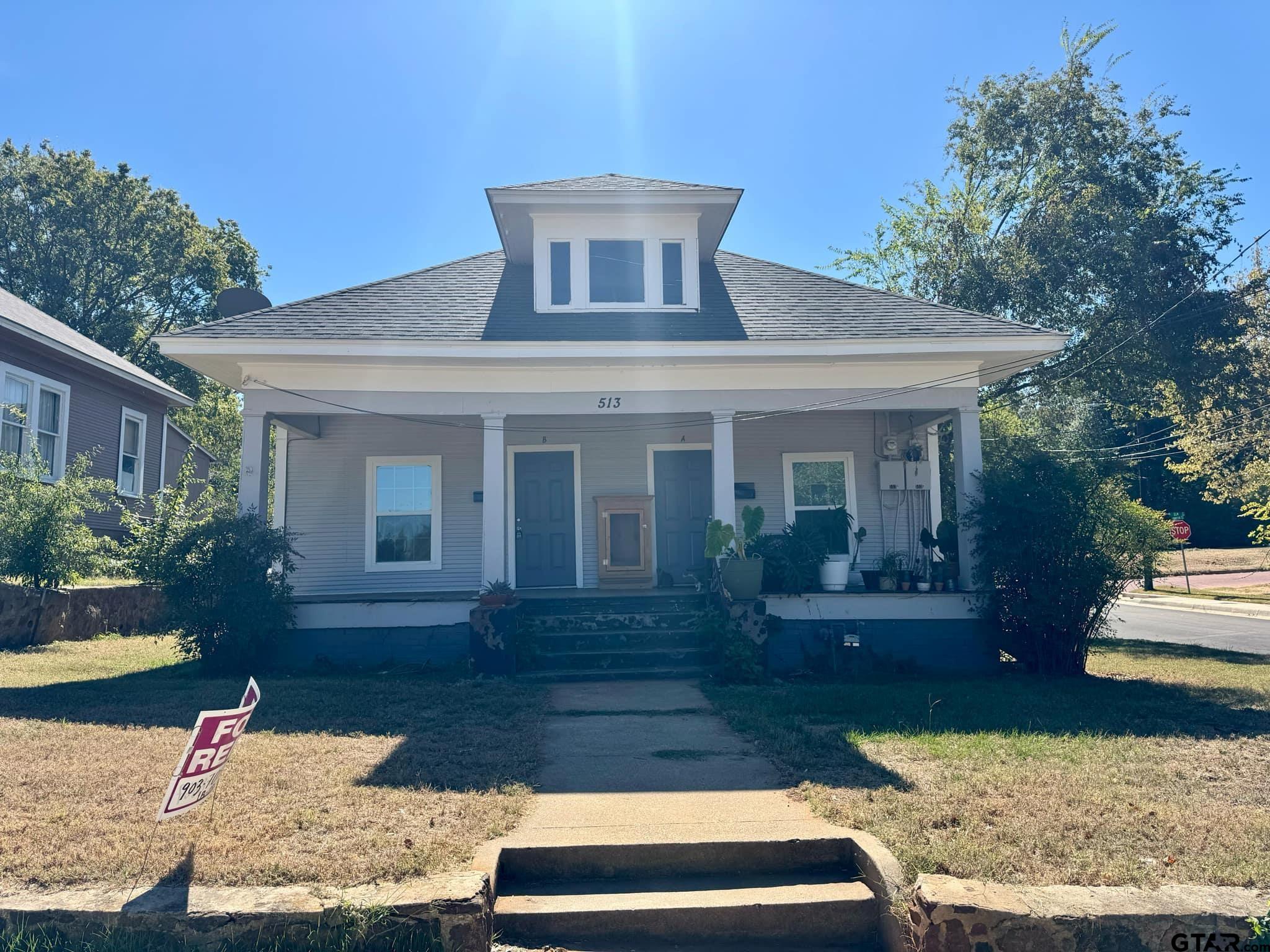 a front view of house with yard and trees in the background