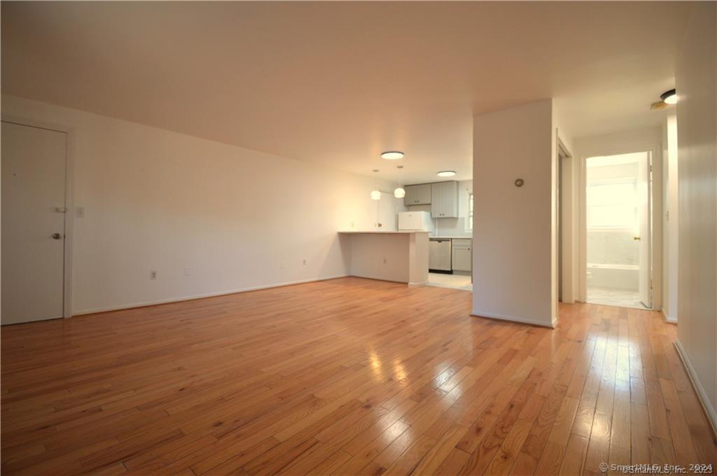 a view of empty room with wooden floor and a window