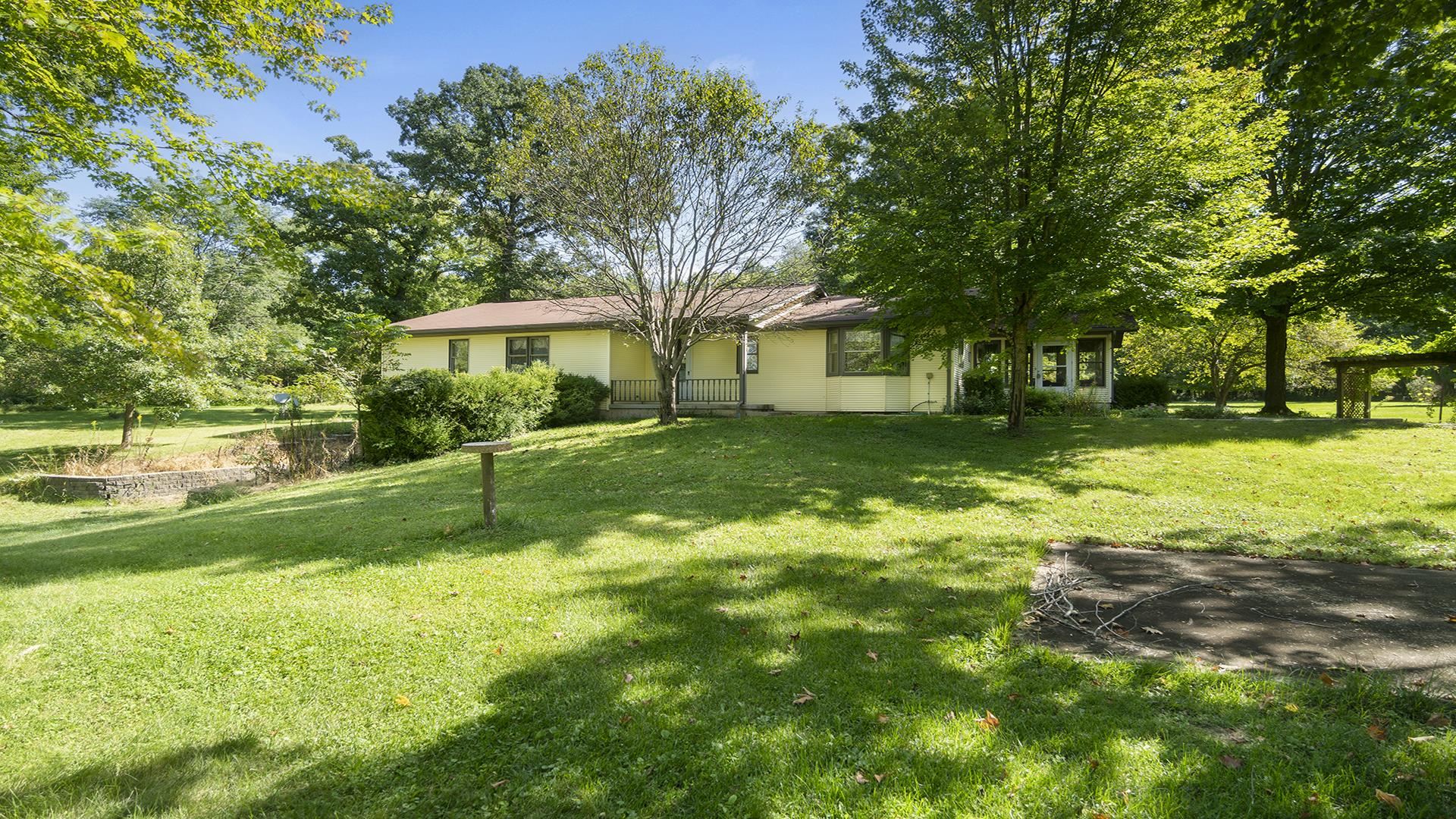 a view of a house with a big yard potted plants and large tree