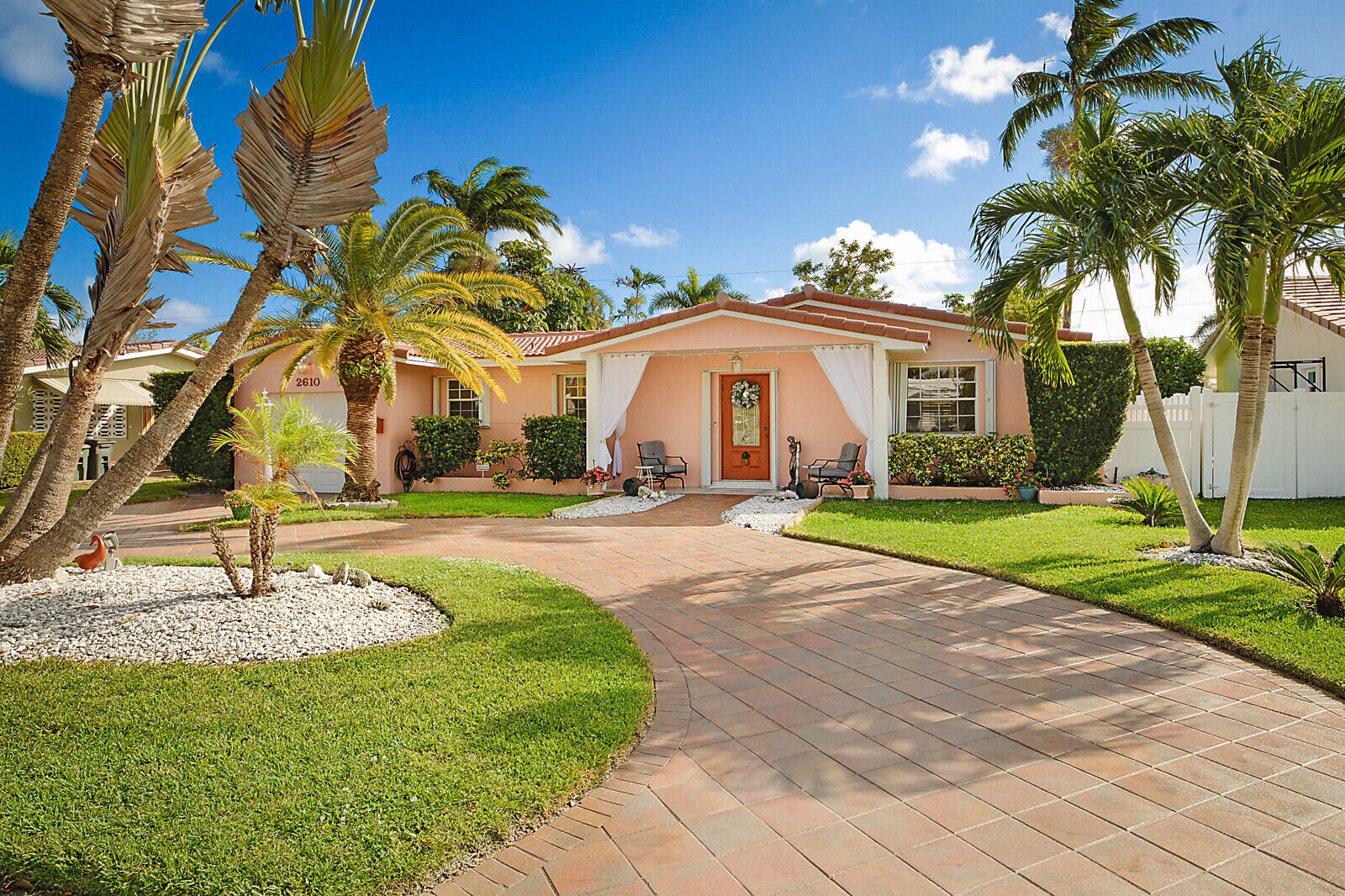 a front view of a house with garden and trees