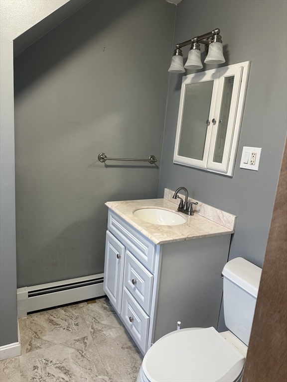 a bathroom with a granite countertop toilet sink and mirror