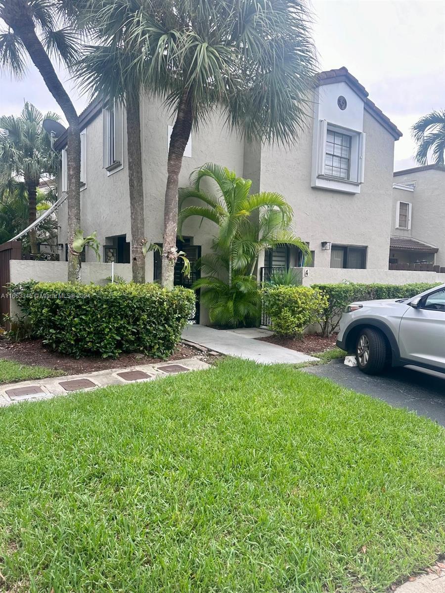 a view of a house with a yard and palm trees