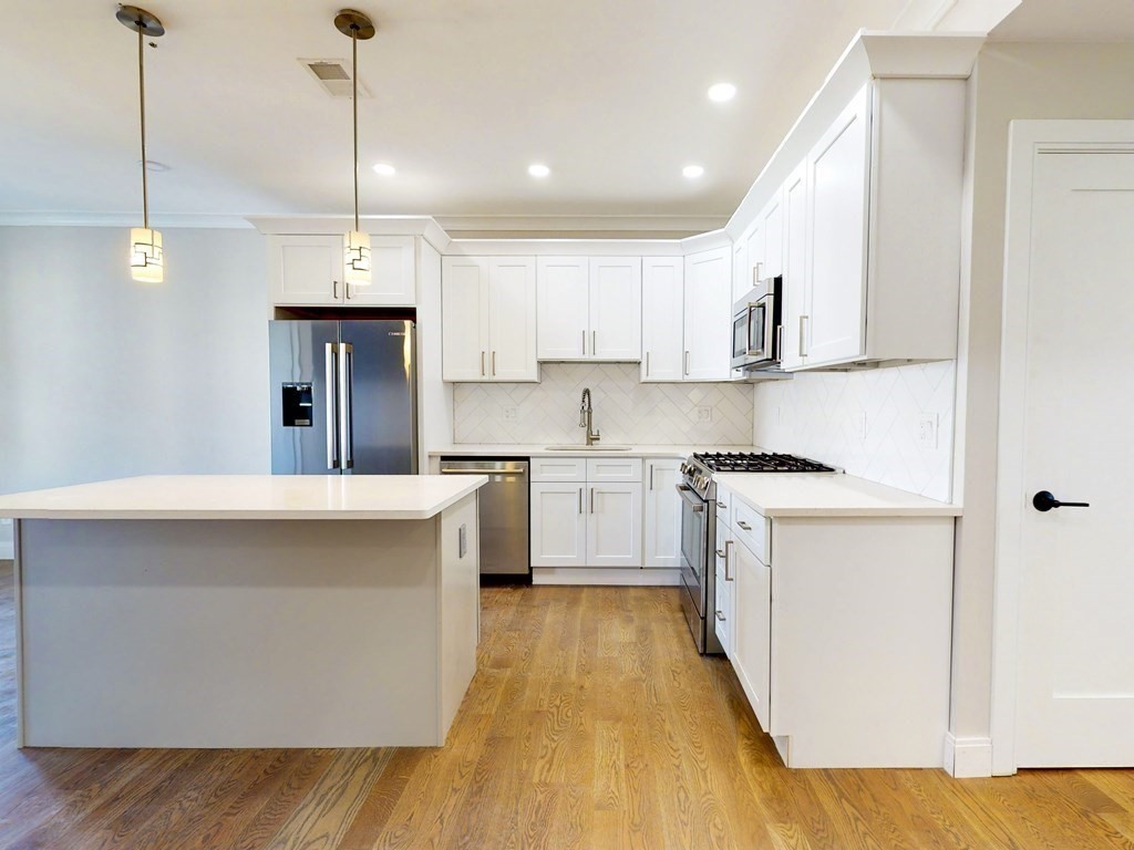 a kitchen with kitchen island a sink a stove a refrigerator and white cabinets