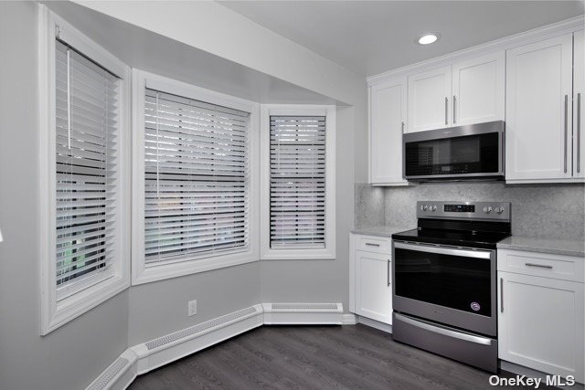 a kitchen with granite countertop a stove a microwave and window