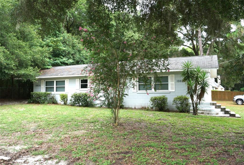 a front view of a house with a garden and trees