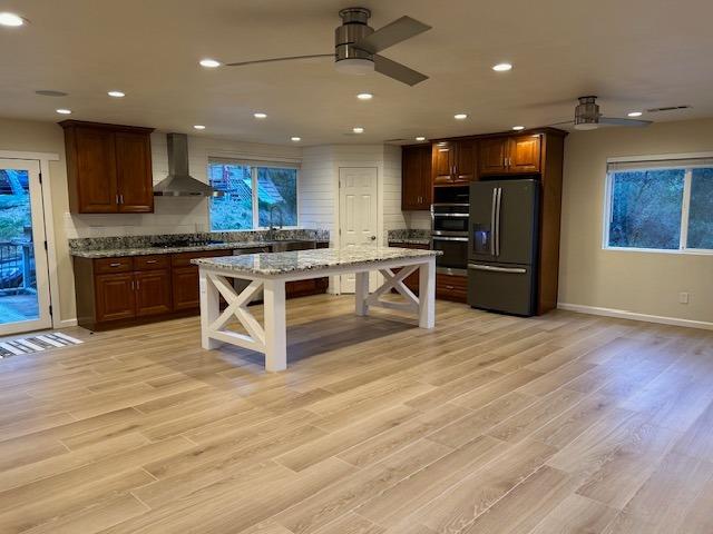 a kitchen with stainless steel appliances granite countertop a stove top oven a sink dishwasher a refrigerator and a dining table with wooden floor