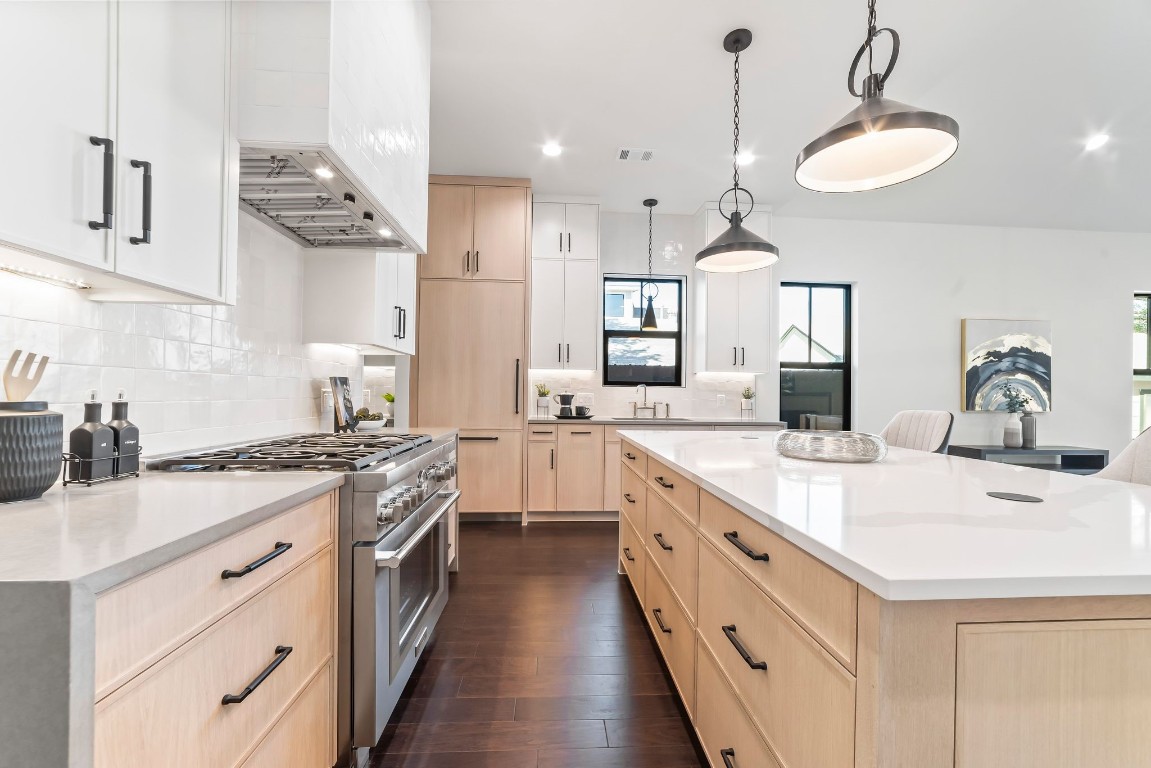 a kitchen with kitchen island granite countertop a sink a stove oven a counter space and cabinets