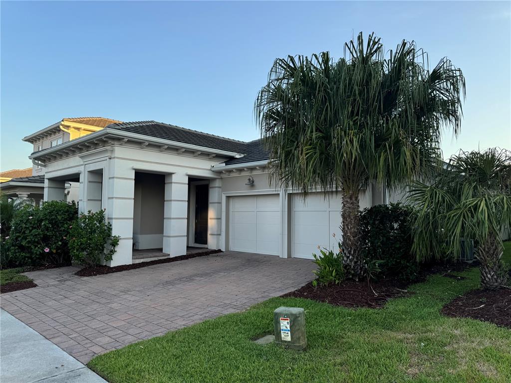 a front view of a house with a garden and palm trees