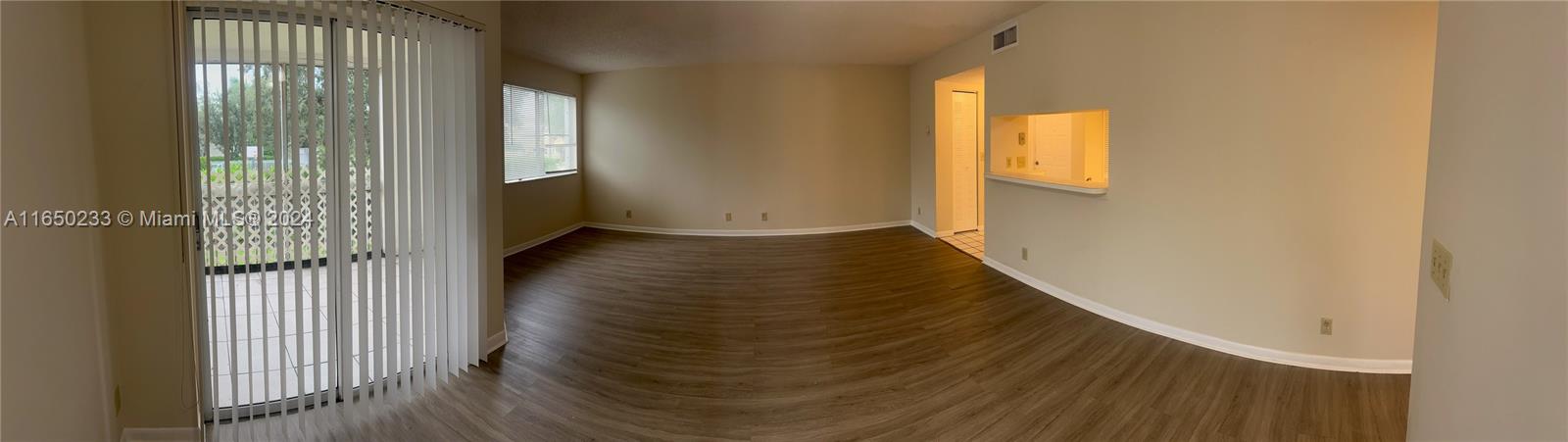 a view of a hallway with wooden floor and windows