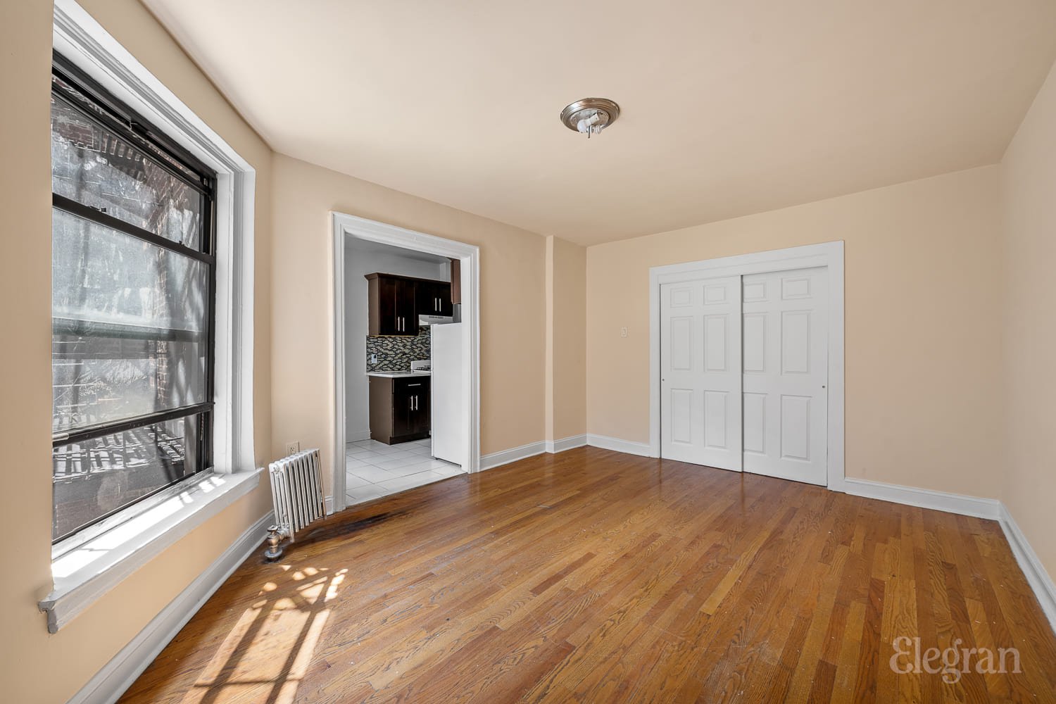 a view of an empty room with a window and wooden floor