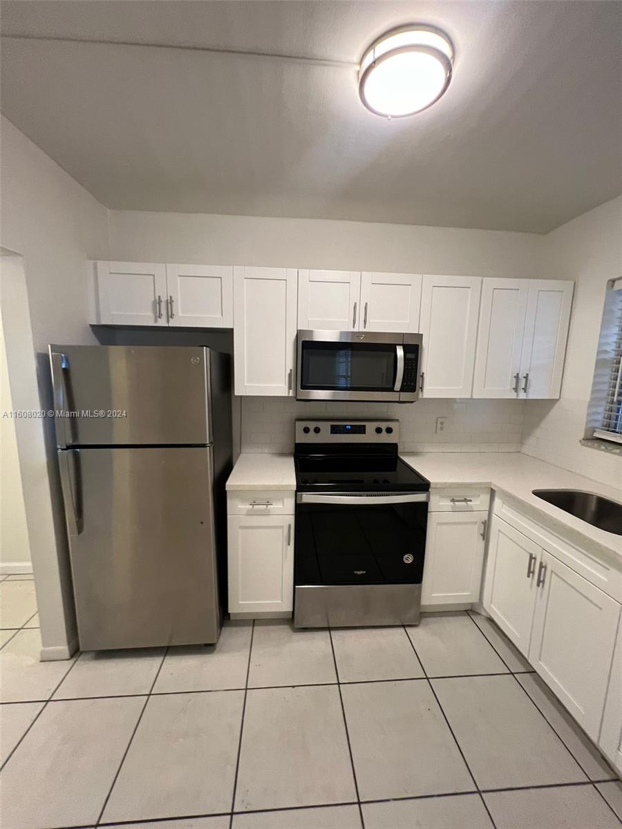 a kitchen with a refrigerator a stove top oven and cabinets