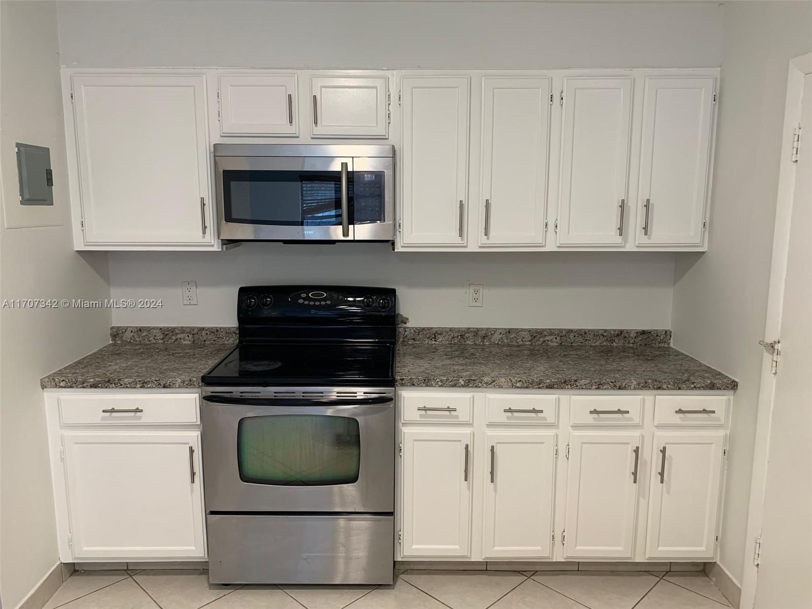 a kitchen with granite countertop white cabinets and stainless steel appliances