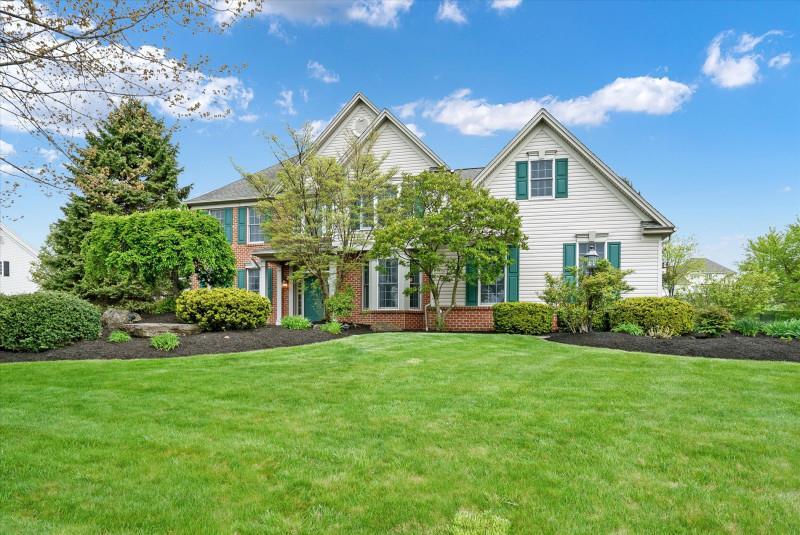 a view of a house with a big yard potted plants and large tree