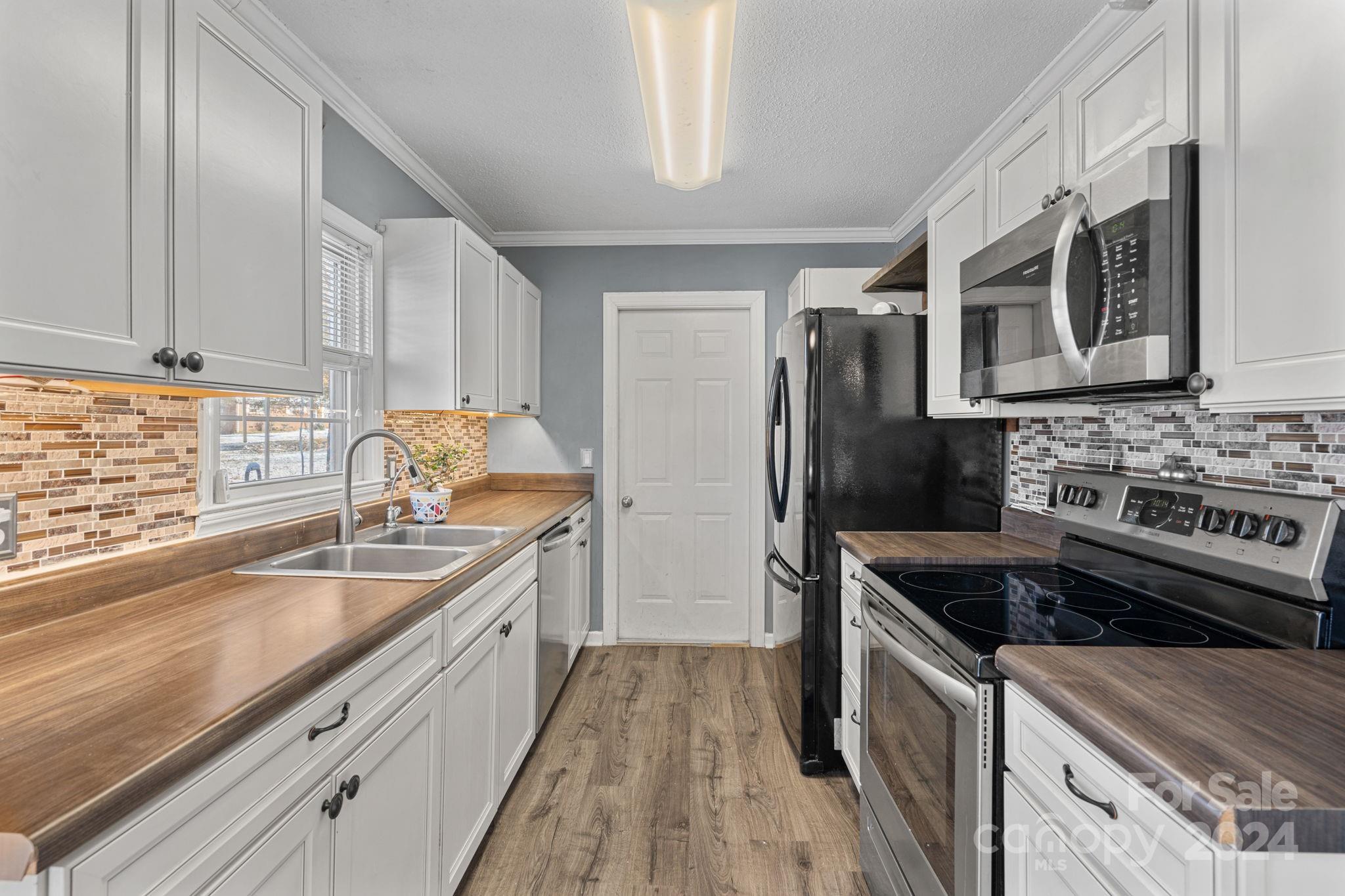 a kitchen with granite countertop a sink stove and refrigerator