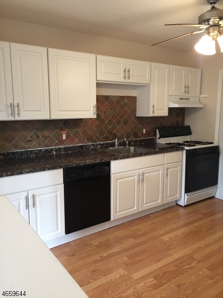 a kitchen with stainless steel appliances granite countertop a stove a sink and white cabinets