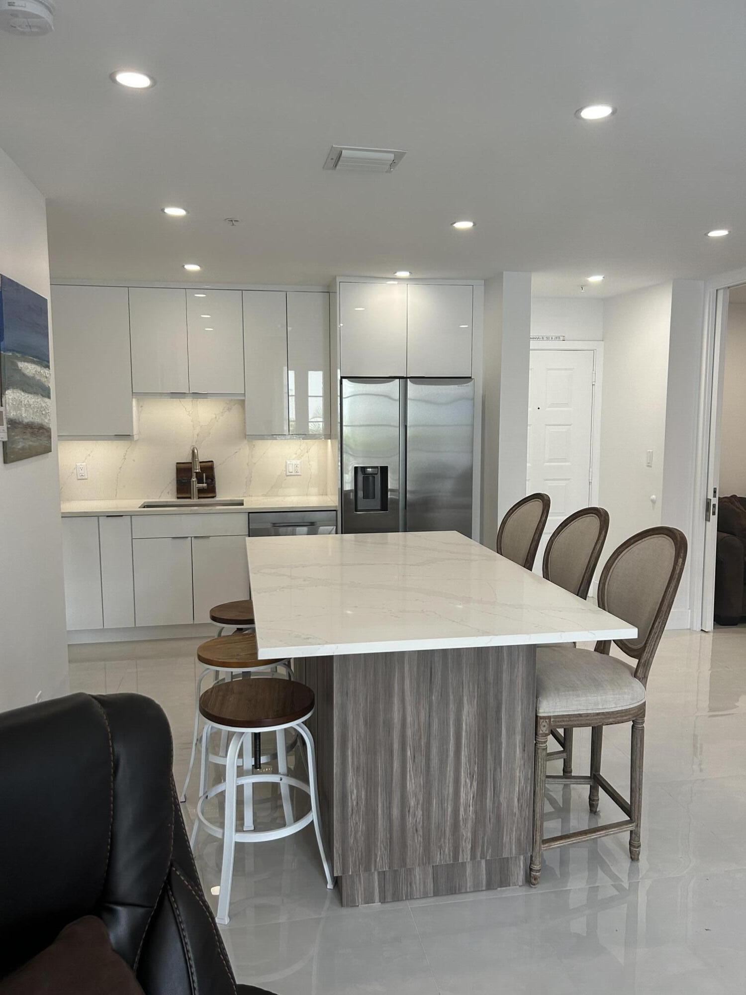 a kitchen with kitchen island a dining table chairs wooden cabinets and white appliances