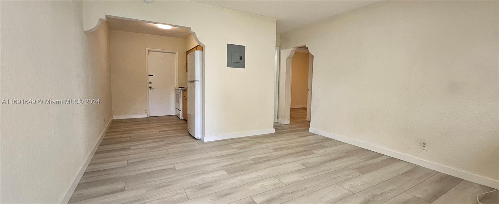 a view of a hallway with wooden floor and a bathroom