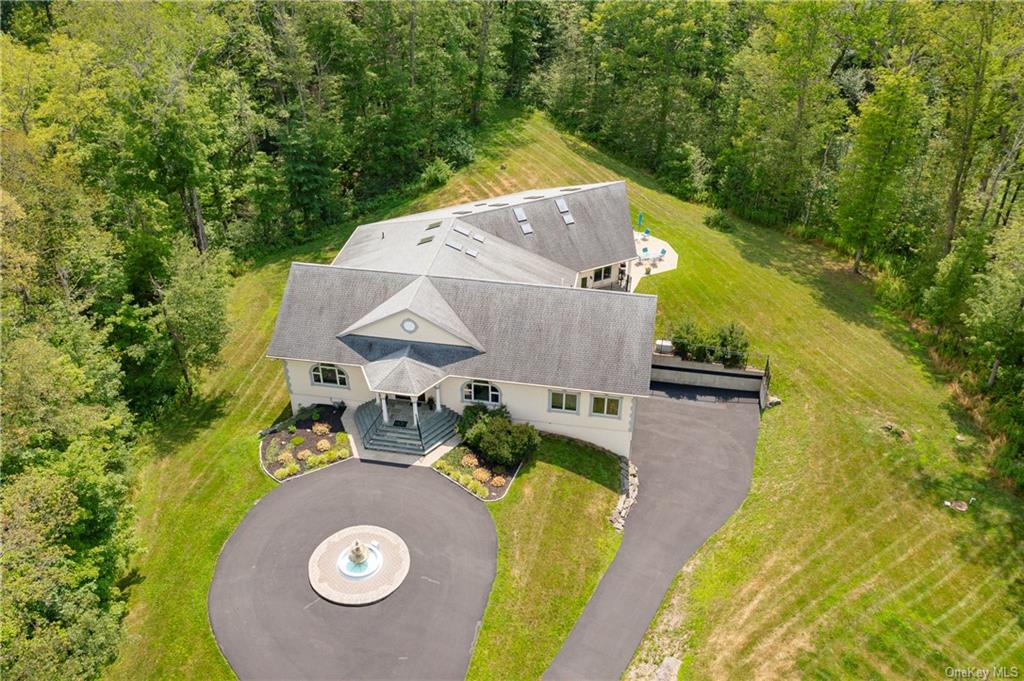 an aerial view of a house with outdoor space and trees all around