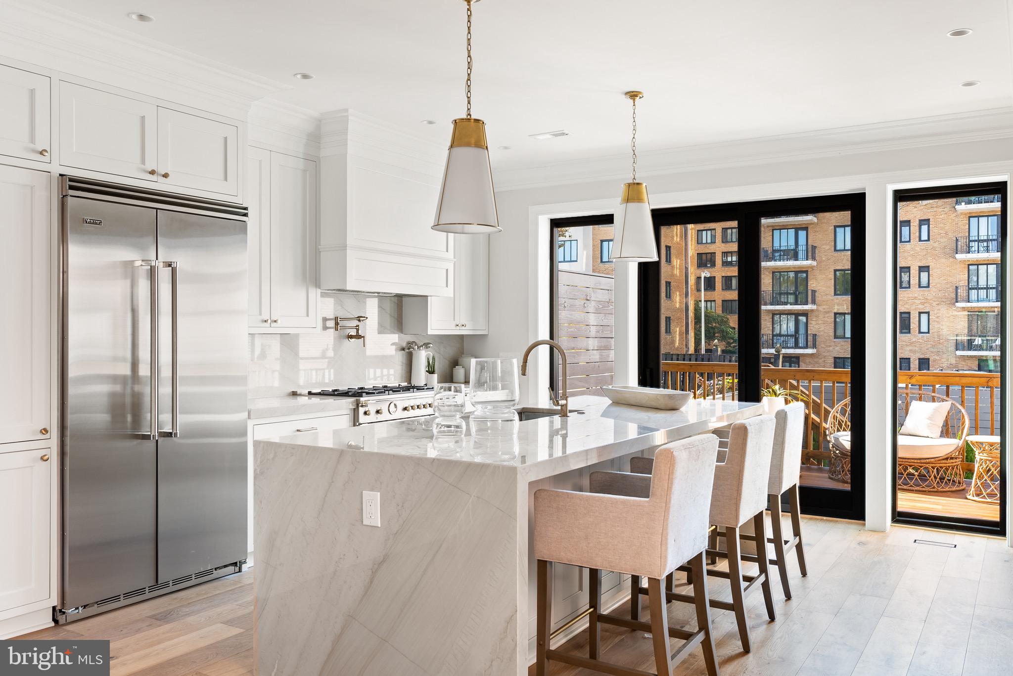 a kitchen with stainless steel appliances granite countertop a refrigerator a sink and a chandelier