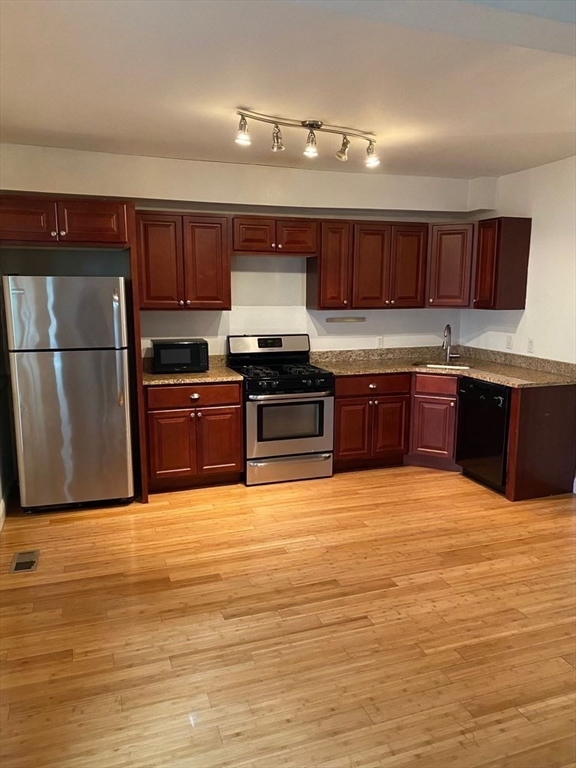 a large kitchen with kitchen island granite countertop a stove top oven a sink and dishwasher