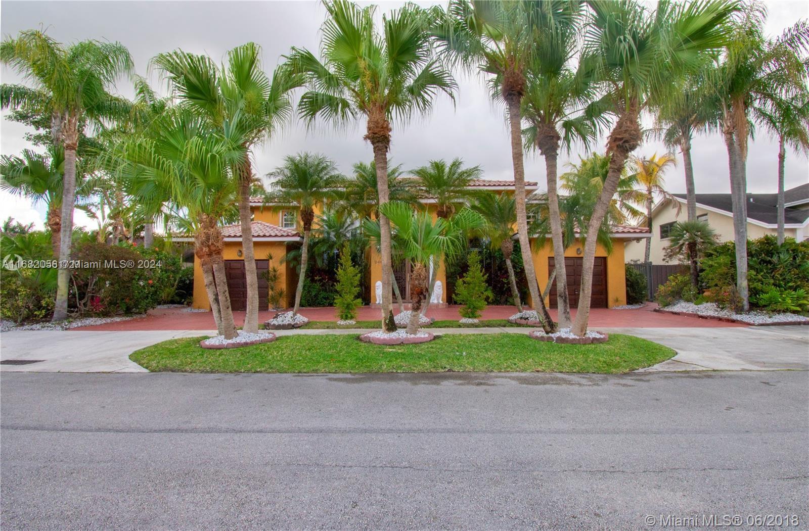 a front view of a house with a yard and palm trees