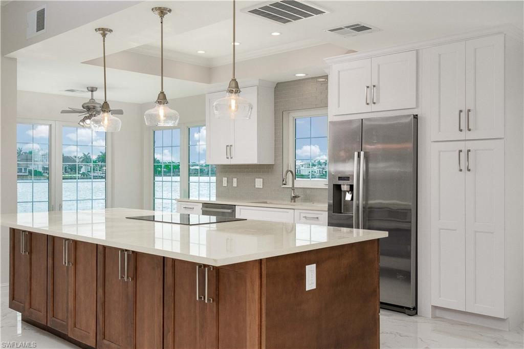 a kitchen with stainless steel appliances granite countertop a refrigerator a sink and white cabinets