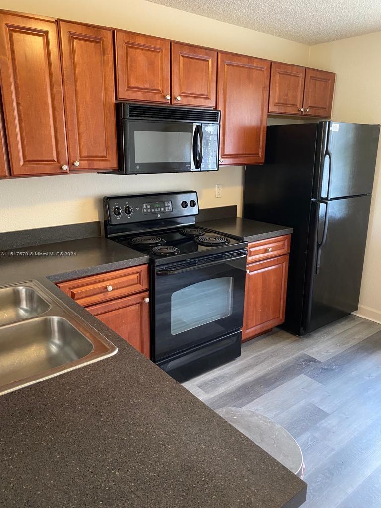 a kitchen with granite countertop a refrigerator stove and microwave